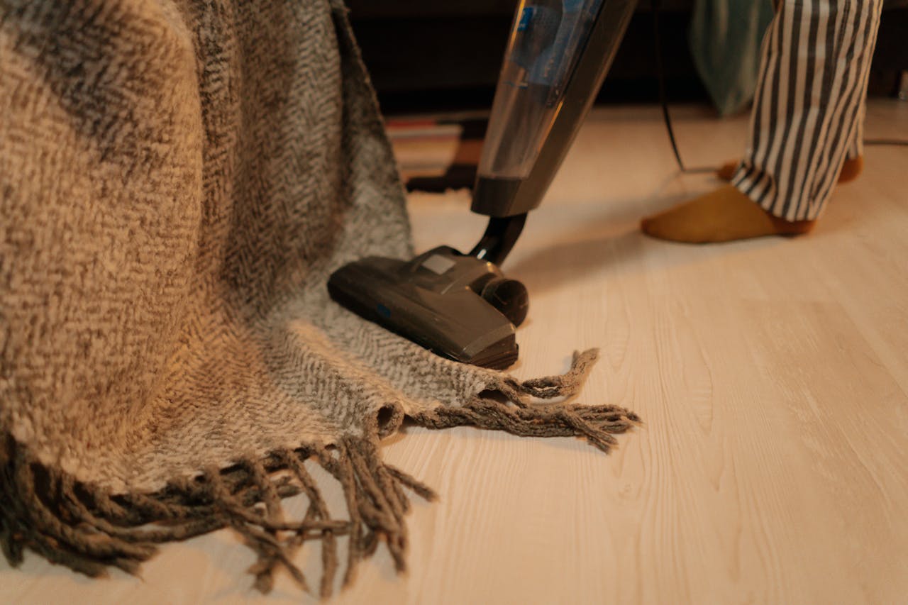 hero-img-01 Close-up of vacuum cleaner cleaning a woolen blanket on the floor indoors.